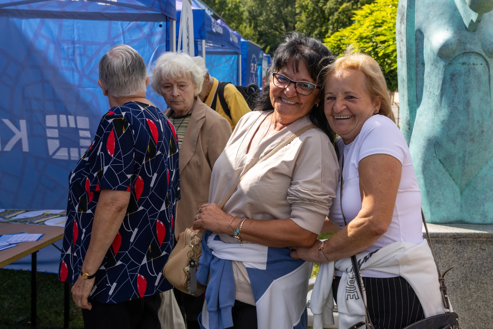 Dwie uśmiechnięte kobiety pozują razem, w tle inne osoby i namioty.  Autor: Bogusław Świerzowski