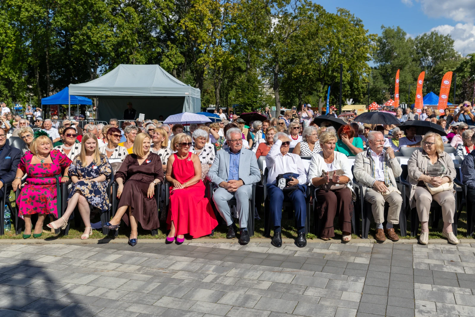 Grupa ludzi siedzących na krzesłach podczas wydarzenia plenerowego w parku.  Autor: Bogusław Świerzowski