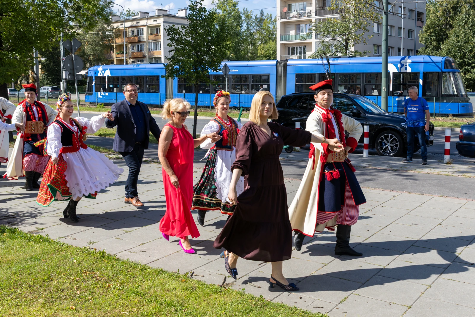 Grupa osób w tradycyjnych strojach ludowych spaceruje po chodniku.  Autor: Bogusław Świerzowski