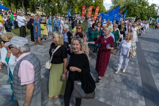 Grupa osób spacerujących po placu, uczestnicy wydarzenia na świeżym powietrzu.