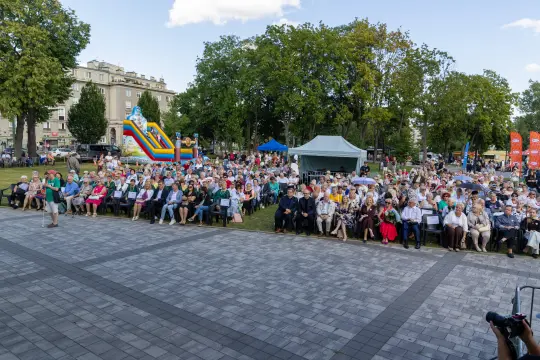 Tłum ludzi na wydarzeniu plenerowym, z atrakcjami dla dzieci w tle.