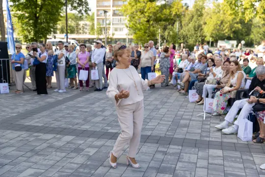 Kobieta tańcząca na tle zgromadzonej publiczności w parku.