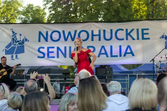 Kobieta w czerwonej sukience śpiewa na scenie podczas festiwalu Nowohuckie Senioralia.