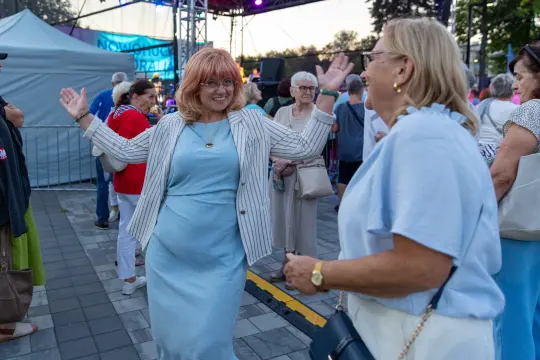 Kobieta w jasnej sukience tańczy na festiwalu, wokół niej tłum ludzi.