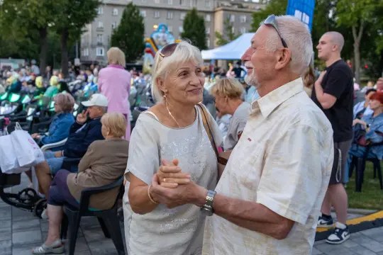 Para tańcząca na tle publiczności w parku.