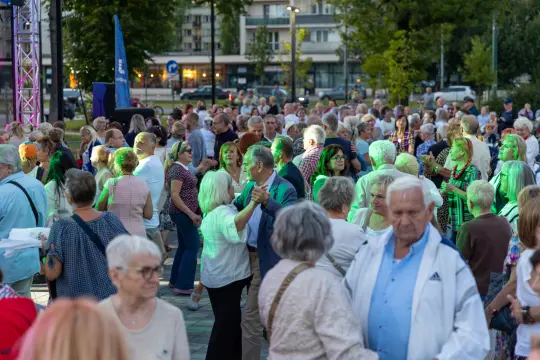 Tłum ludzi tańczących na otwartym terenie podczas wydarzenia kulturalnego.