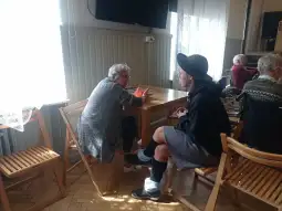 Dwie kobiety rozmawiają przy stole w jasnym pomieszczeniu.