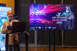 Mężczyzna prezentujący wydarzenie Lord of Lasers w Krakowie, z grafiką na ekranie.