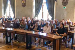 Grupa ludzi siedzących w sali konferencyjnej podczas wydarzenia.