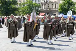 Muzycy w mundurach grający na instrumentach podczas parady na ulicy.