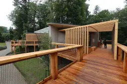 Nowoczesna architektura z drewnianymi tarasami w otoczeniu zieleni.