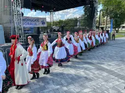 Grupa tancerzy w tradycyjnych strojach ludowych podczas występu na scenie.