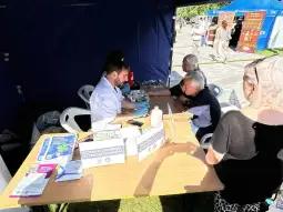 Punkt pomiaru ciśnienia krwi z osobami czekającymi na badanie.