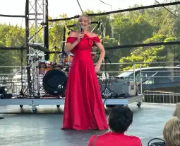 Kobieta w czerwonej sukni wieczorowej występuje na scenie.