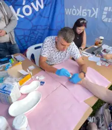 Mężczyzna w rękawiczkach wykonuje badanie medyczne na ręce pacjenta.