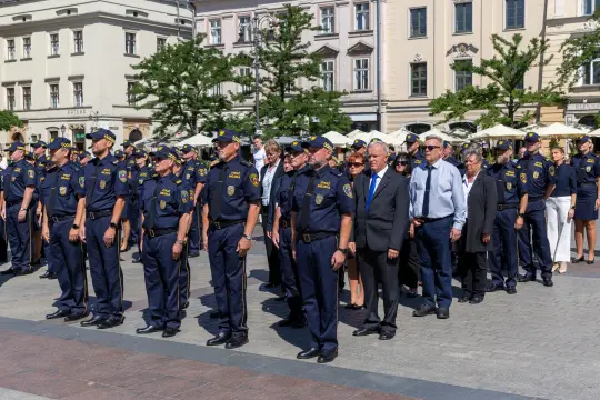 Grupa policjantów i urzędników podczas ceremonii na placu.