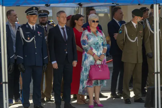 Uroczystość z udziałem przedstawicieli służb mundurowych i gości w eleganckich strojach.