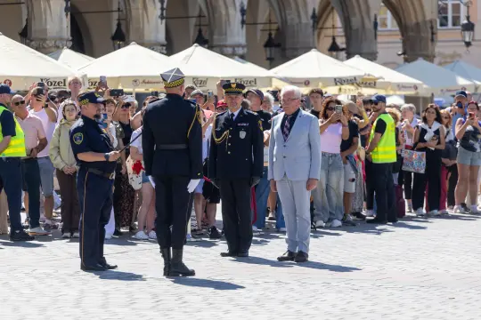 Ceremonia z udziałem funkcjonariuszy i tłumu obserwujących na placu.