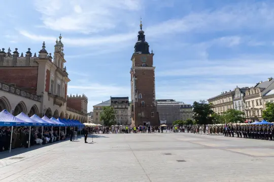 Ratusz w Krakowie z tłumem ludzi i flagami na placu.