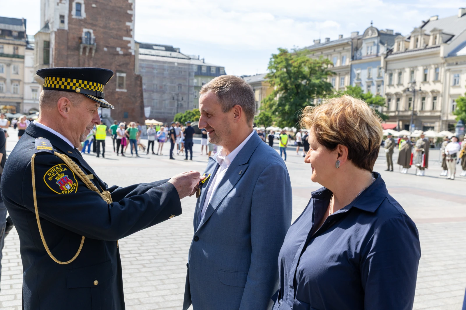 Ceremonia wręczenia odznaczeń na placu, uczestnicy w mundurach i eleganckich strojach.  Autor: Bogusław Świerzowski