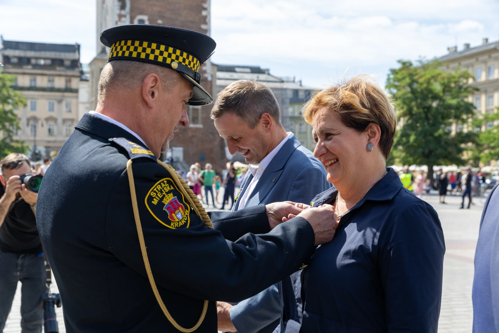 Wręczenie odznaczenia przez funkcjonariusza policji kobiecie w eleganckim stroju.  Autor: Bogusław Świerzowski