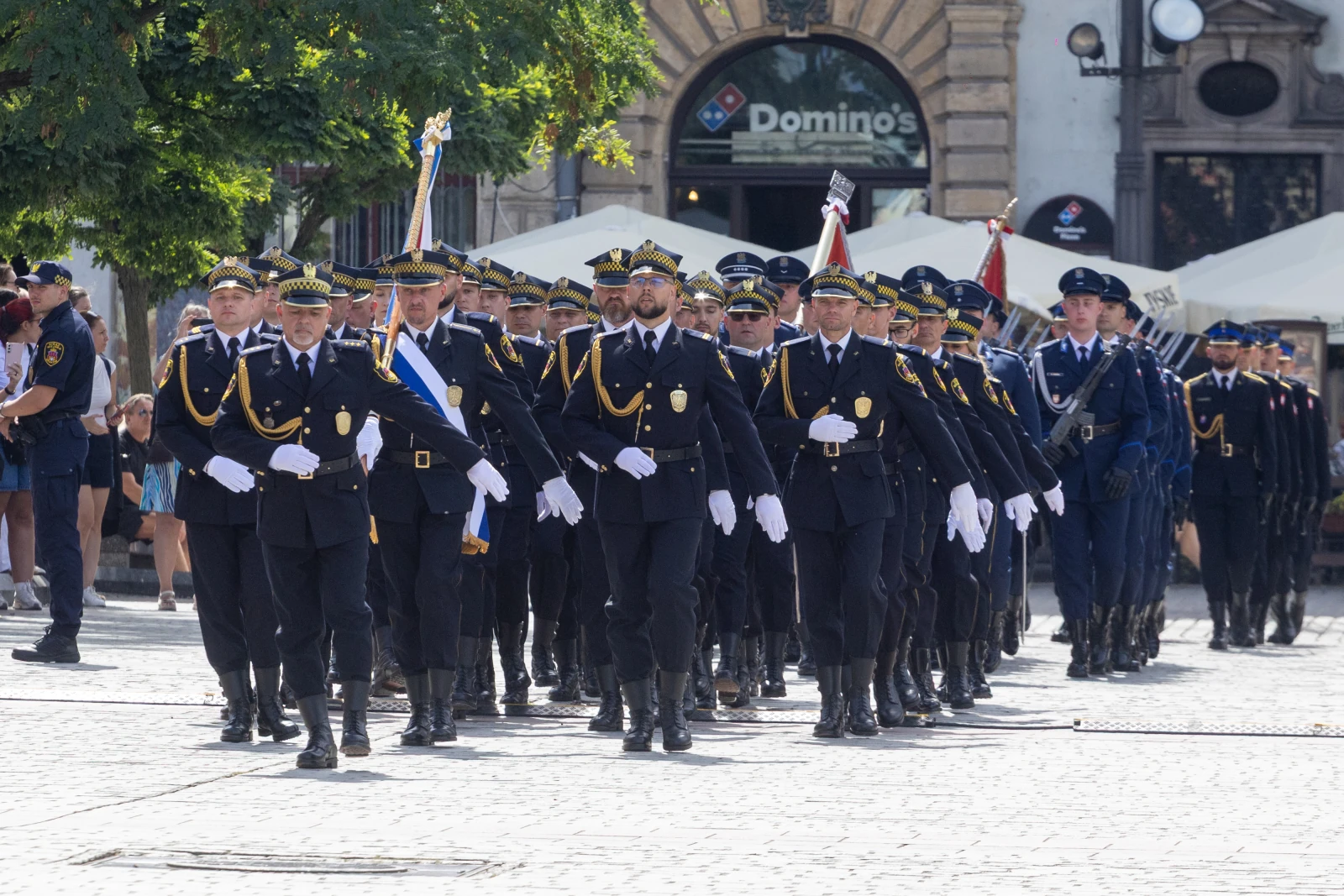 Parada policji w mundurach, z flagami, na ulicy w słoneczny dzień.  Autor: Bogusław Świerzowski