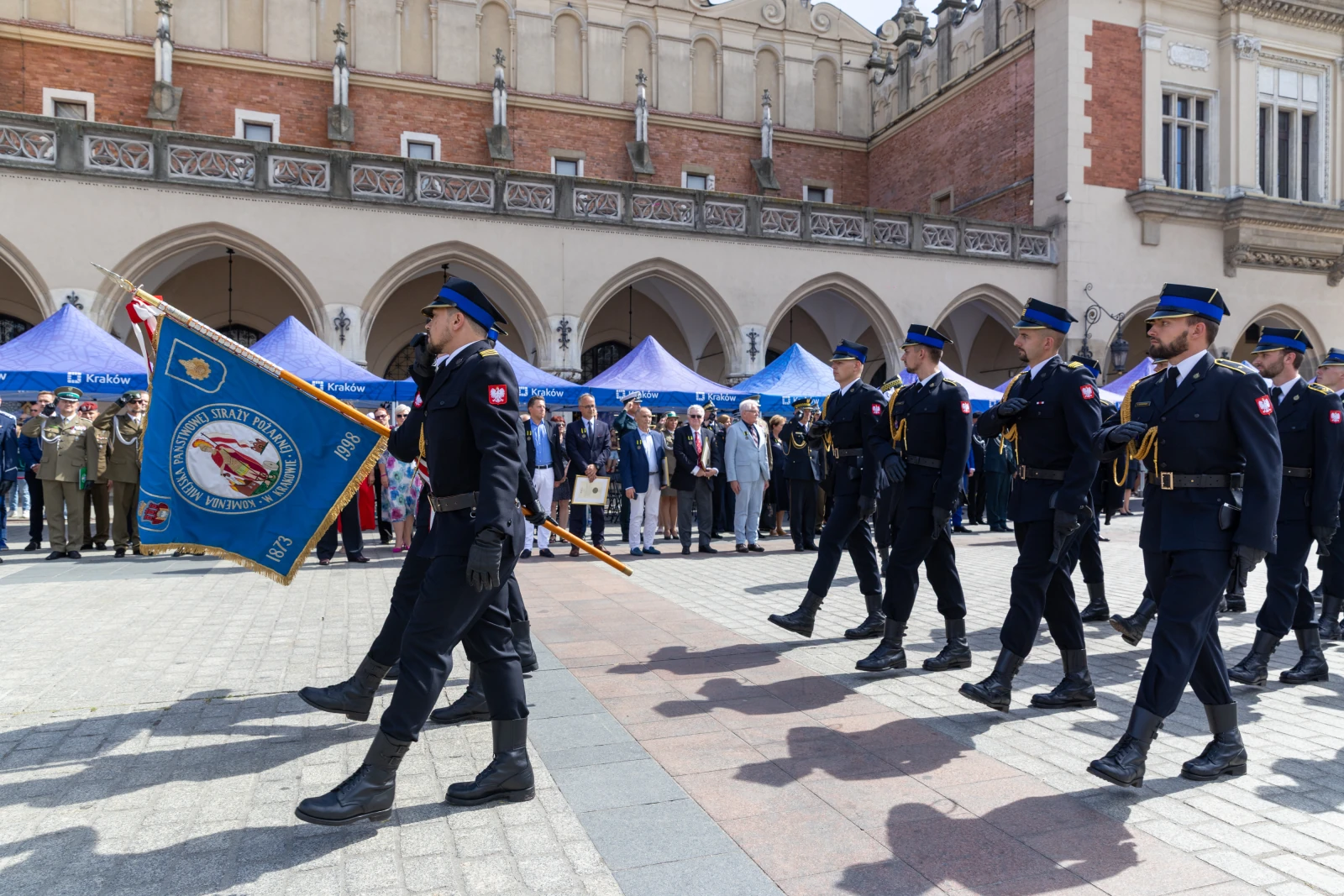 Parada z udziałem policji, mundurowi niosą sztandar przed tłumem ludzi.  Autor: Bogusław Świerzowski