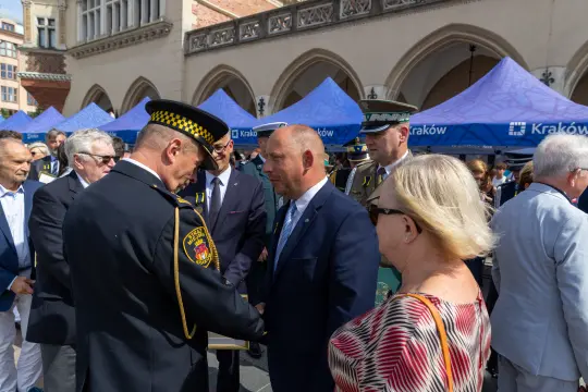 Spotkanie przedstawicieli władz z mieszkańcami, w tle namioty z logo Krakowa.