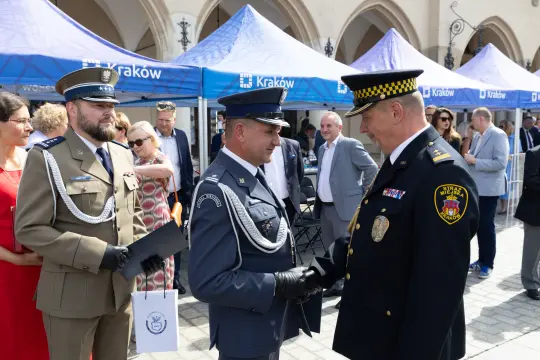Dwaj mężczyźni w mundurach uścisną ręce podczas ceremonii w Krakowie.