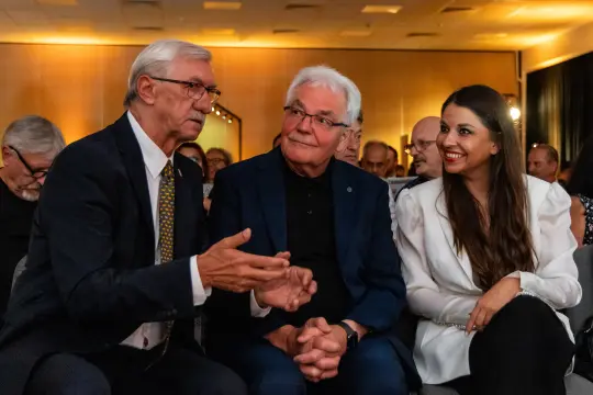Trzech mężczyzn i kobieta rozmawiają w sali konferencyjnej.