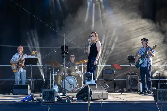 Zespół muzyczny występujący na scenie, wokalistka śpiewa, instrumentaliści grają.