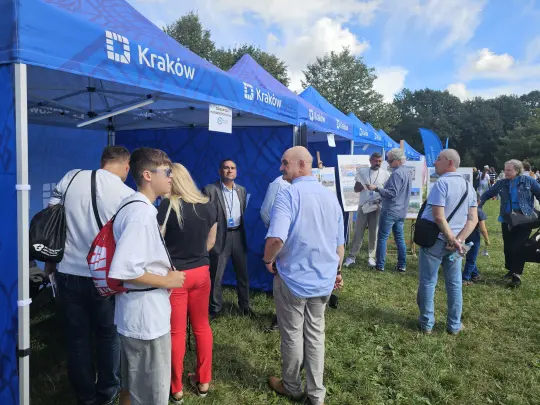 Ludzie rozmawiają przy stoiskach promocyjnych w Krakowie.