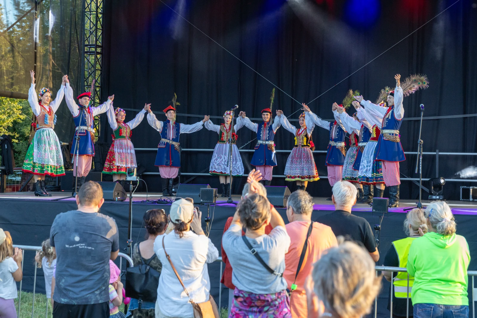 Grupa tancerzy w tradycyjnych strojach ludowych tańczy na scenie przed publicznością.  Autor: Bogusław Świerzowski