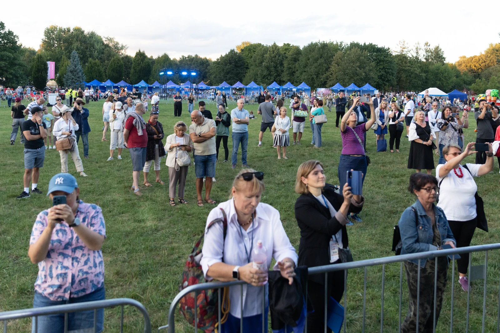 Tłum ludzi na festiwalu, niektórzy trzymają telefony, w tle namioty i scena.  Autor: Bogusław Świerzowski