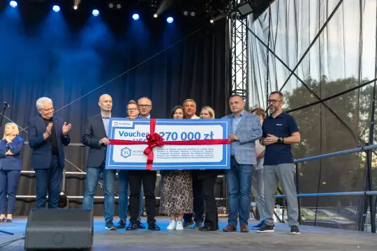 Wręczenie czeku na 370 000 zł podczas wydarzenia na scenie.