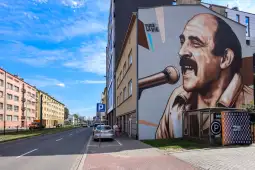 Murale z wizerunkiem mężczyzny śpiewającego do mikrofonu na ścianie budynku.