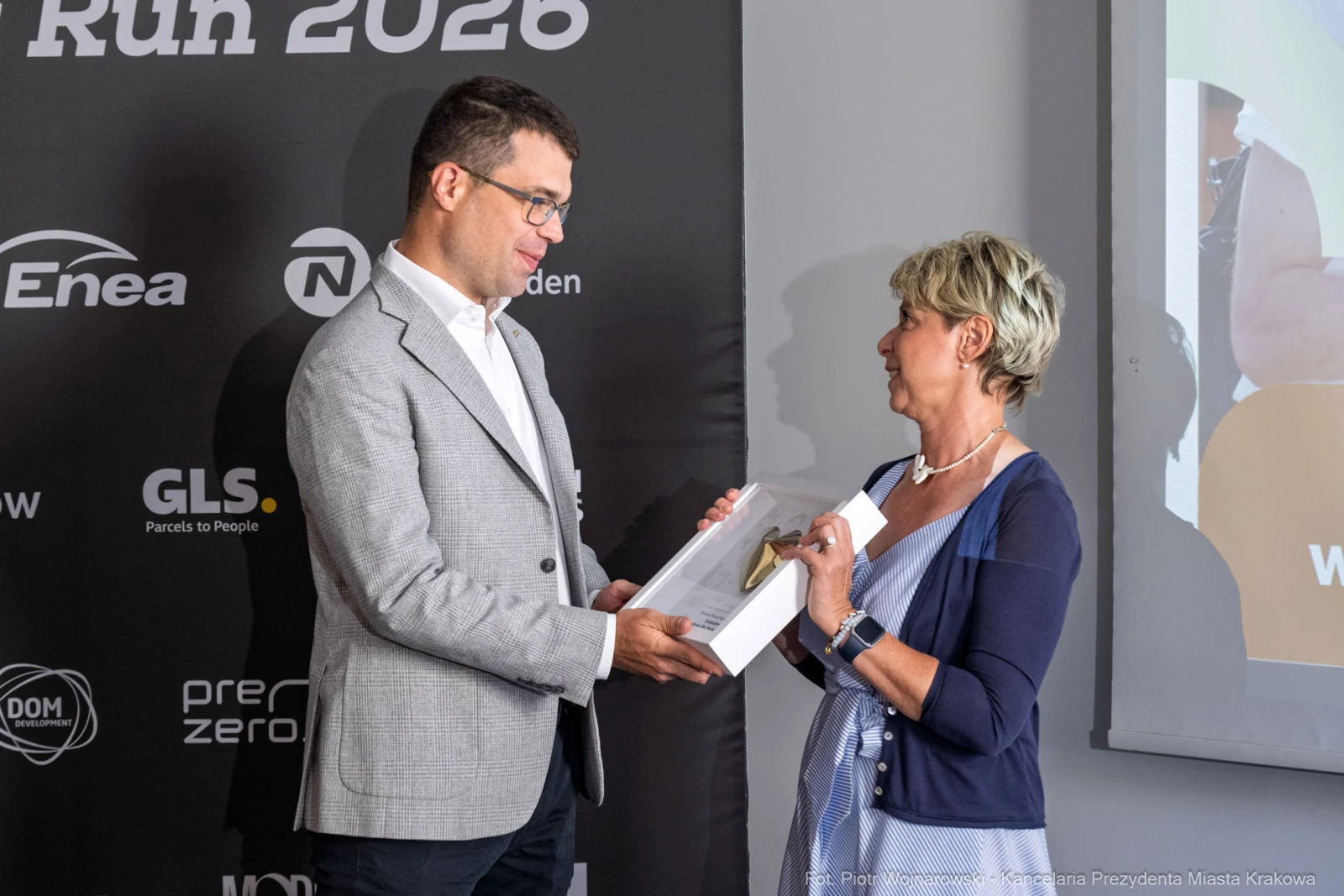 Mężczyzna wręcza nagrodę kobiecie podczas wydarzenia promującego bieg w Krakowie.  Autor: Piotr Wojnarowski