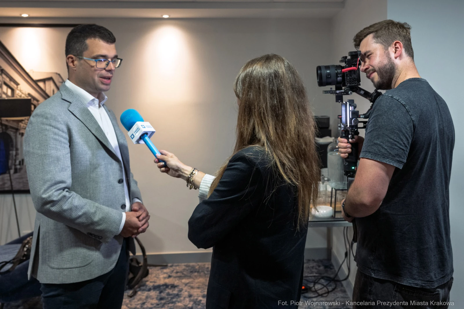 Wywiad z mężczyzną w garniturze, dziennikarka z mikrofonem, operator kamery.  Autor: Piotr Wojnarowski