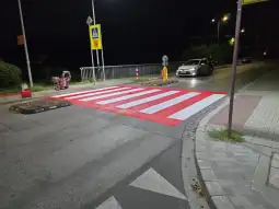 Przejazd dla pieszych z czerwonymi pasami na drodze nocą.