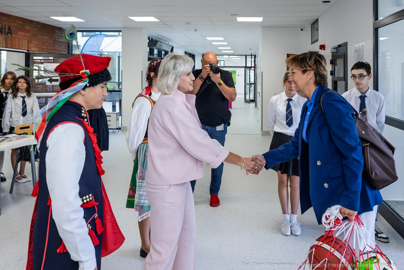Spotkanie dwóch kobiet w eleganckich strojach, w tle młodzież w tradycyjnych ubraniach.  Autor: Piotr Wojnarowski
