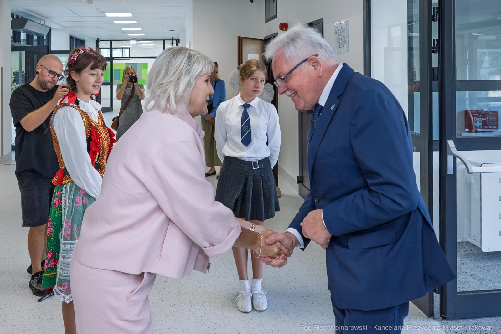Spotkanie dwóch osób podczas ceremonii, w tle młodzież w strojach szkolnych i ludowych.  Autor: Piotr Wojnarowski