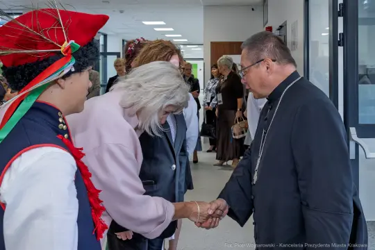 Spotkanie osób w tradycyjnych strojach, wymiana uścisków dłoni.