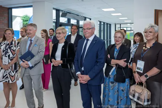 Grupa osób w formalnych strojach podczas wydarzenia w nowoczesnym wnętrzu.