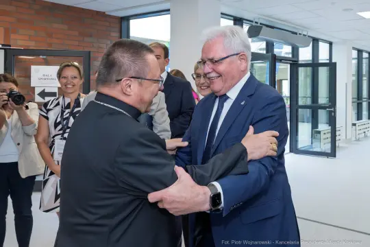 Spotkanie dwóch mężczyzn w formalnych strojach, uściski i uśmiechy.