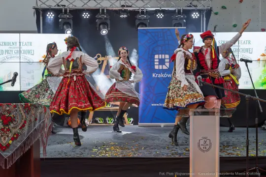 Tancerki w tradycyjnych strojach ludowych wykonujące taniec na scenie.