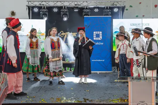 Uczniowie w strojach ludowych występują na scenie podczas szkolnego przedstawienia.