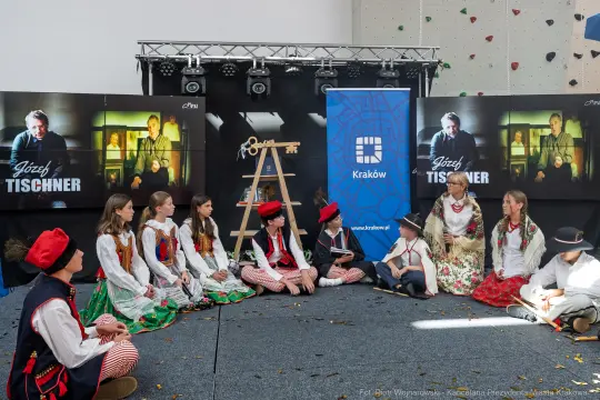 Grupa osób w tradycyjnych strojach ludowych podczas wydarzenia kulturalnego w Krakowie.