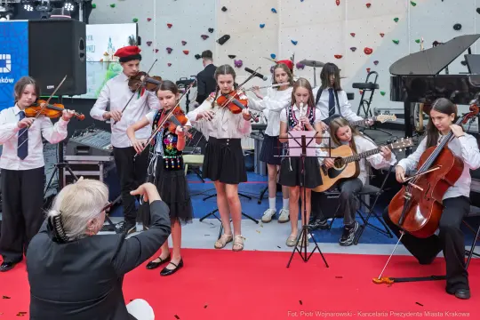 Młodzieżowy zespół muzyczny grający na instrumentach w sali koncertowej.