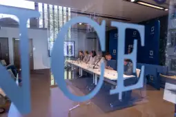 Konferencja z panelistami siedzącymi przy stole, z widocznymi mikrofonami i ekranem w tle.