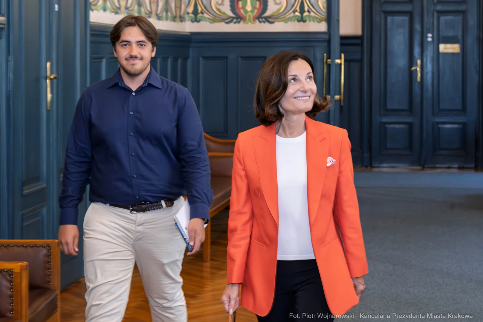 Kobieta w pomarańczowej marynarce i mężczyzna w granatowej koszuli w eleganckim wnętrzu.  Autor: Piotr Wojnarowski